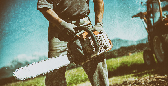 Man Cutting Firewoods With Electric Chainsaw