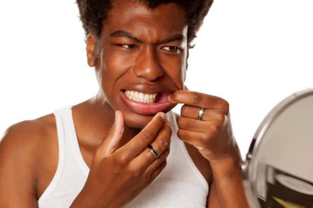 istock young handsome afro american guy checking his teeth in mirror on white background 1049247916
