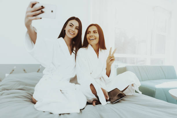 istock Girls In A Bathrobes Are Doing A Selfie On A Bed. 1049248622