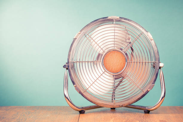 Retro portable office or home cooling fan in working mode standing on table. Vintage instagram style filtered photo stock photo