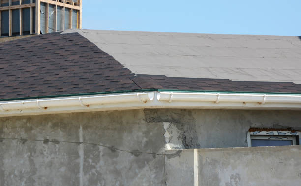 istock Installing asphalt shingles. Roof repair with unfinished rain gutter. Roofing construction with roof tiles, asphalt shingles. 1049251382