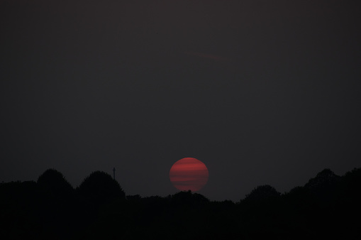Cross in silhouette with sinking red sun