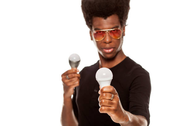 istock young handsome afro american guy holding LED bulbs isolated on white background. saving energy concept 1049258532