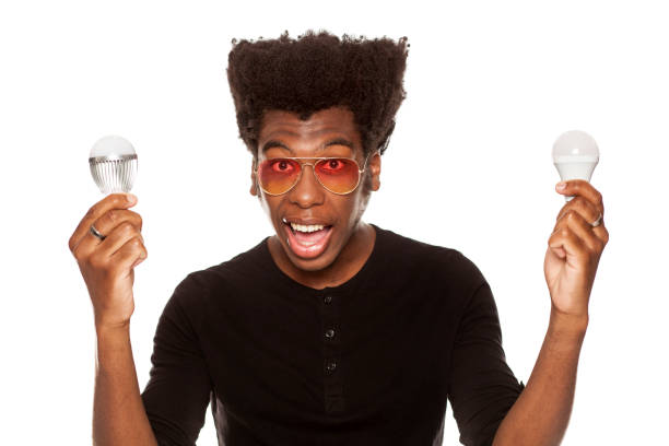 istock young handsome afro american guy holding LED bulbs isolated on white background. saving energy concept 1049258542
