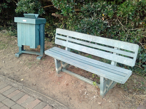 Recycled plastic used to manufacture new park bench and waste bin used beside walkway for convenience of tourists and holidaymakers