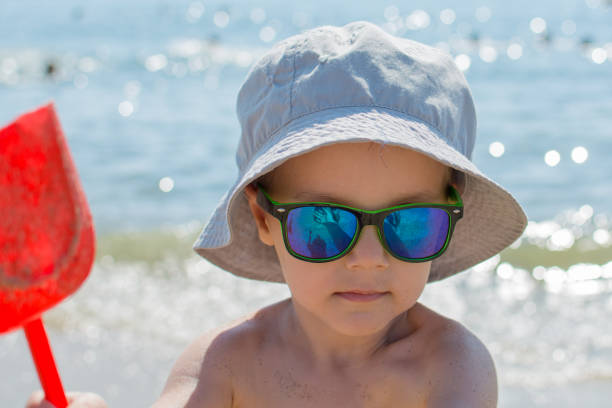 istock The boy with a hat and a shovel is playing on the beach 1049262560