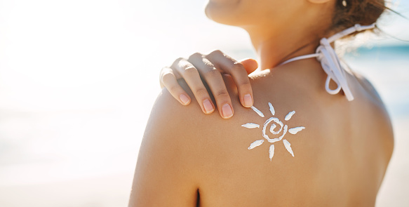 Cropped shot of a young woman posing with suntan lotion on her shoulder