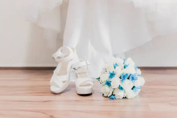 White wedding shoes, white and blue bouquet with roses and chrysanthemums and white wedding dress