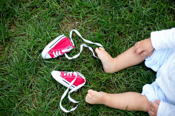 rote baby kleinkinder sneakers und weiße frau turnschuhe auf dem rasen mit babys füße - shoe women adult baby stock-fotos und bilder