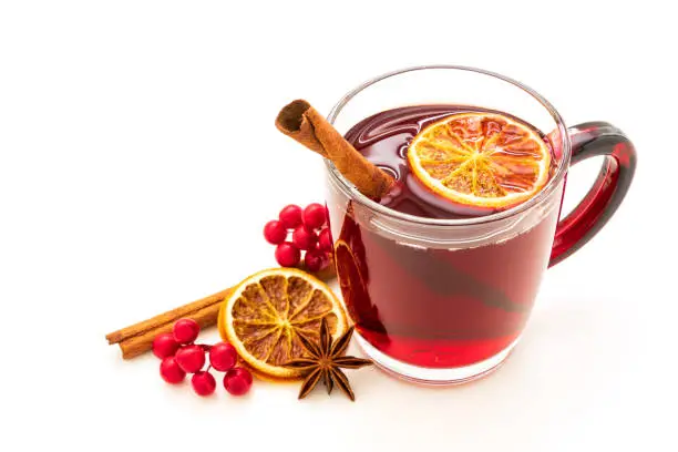 Hot red mulled wine isolated on white background with christmas spices, orange slice, anise and cinnamon sticks.