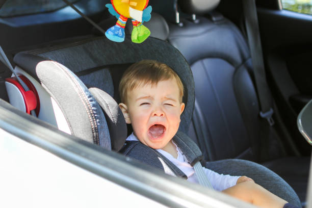 작은 사내 아이 그의 자동차 좌석에 앉아 기꺼이 하지에 울으십시오. 아이 아기 안전 개념으로 여행. 작은 여객 수송 - baby human face child innocence 뉴스 사진 이미지