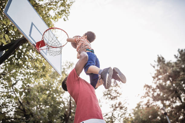 Father and son having fun, playing basketball outdoors stock photo