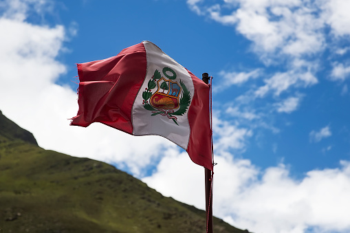Peruvian flag waving under blue sky in Cusco, Peru