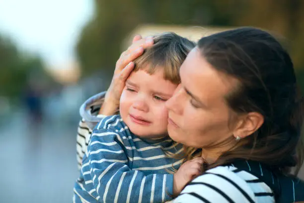 Photo of the child cries on hands at mother on walk