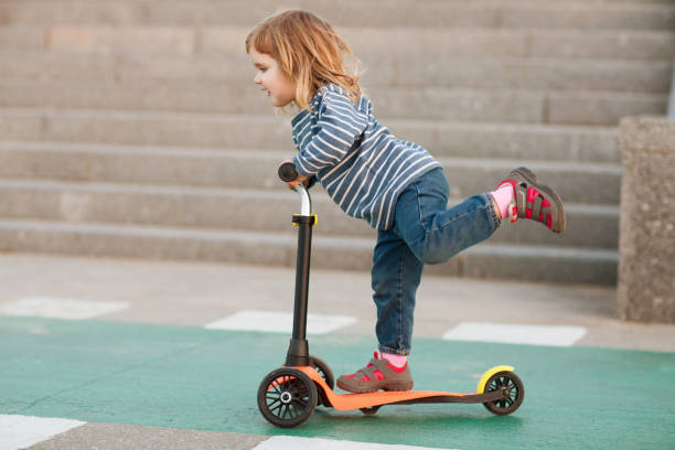 glückliches positive kind auf dem roller in der stadt - tretroller stock-fotos und bilder