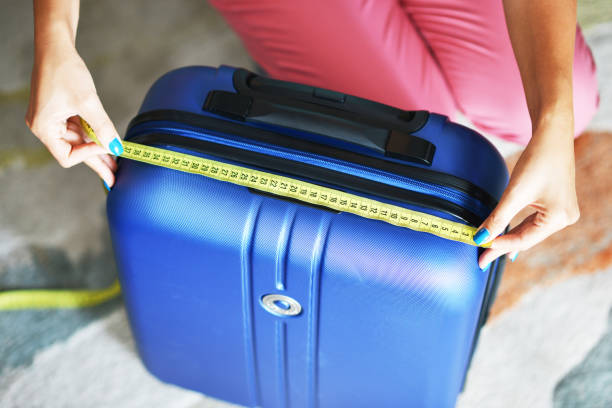 Young woman measuring travel luggage or suitcase before flight stock photo