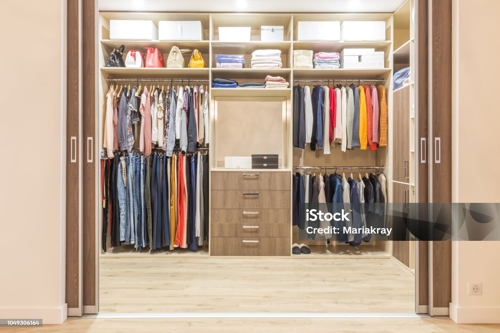 Modern wooden wardrobe with clothes hanging on rail in walk in closet Modern wooden wardrobe with clothes hanging on rail in walk in closet design interior Closet Stock Photo