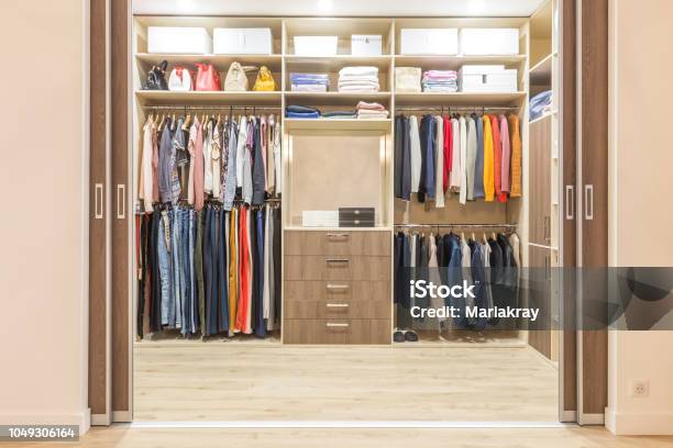 Modern Wooden Wardrobe With Clothes Hanging On Rail In Walk In Closet Stock Photo - Download Image Now