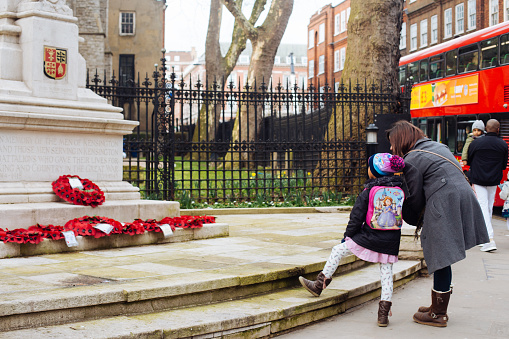 London, UK - March 11, 2018: Mum and daughter looking at the Kensington War Memorial on the intersection of Kensington Church Street and Kensington High Street near St Mary Abbots Church in London, UK