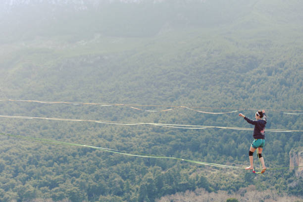 Highliner on a rope. Highline on a background of mountains. Extreme sport on the nature. Balancing on the sling. Equilibrium at altitude. Highliner on a rope. Highline on a background of mountains. Extreme sport on the nature. Balancing on the sling. Equilibrium at altitude. highlining stock pictures, royalty-free photos & images