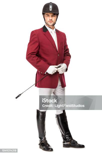 Handsome Young Horseman In Uniform Holding Horseman Stick And Looking At Camera Isolated On White Stock Photo - Download Image Now