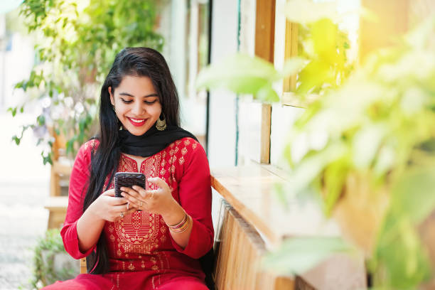 Indian girl with phone Pretty young indian woman using her phone and looking at camera culture of india stock pictures, royalty-free photos & images
