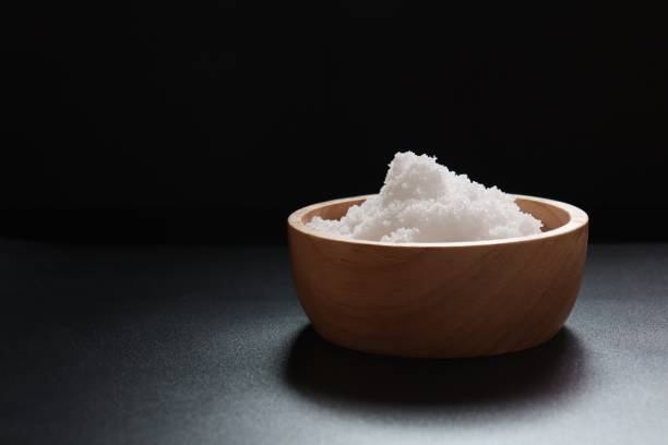 istock Salt in a wooden bowl in dark background 1049325224