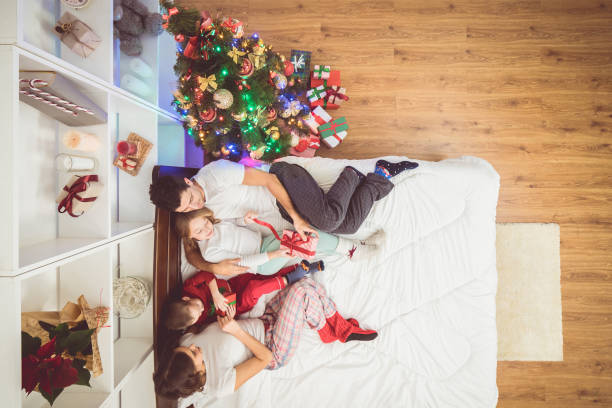 l’heureuse famille étends sur le lit avec une boîtes à cadeaux. découvre d’en haut - placard holding celebration women photos et images de collection