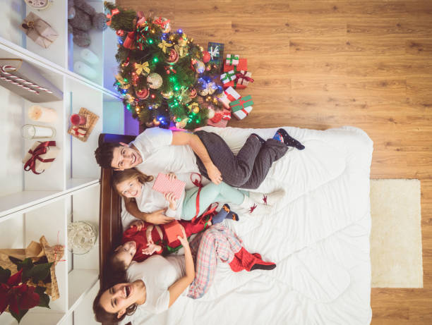 l’heureuse famille étends sur le lit avec une boîtes à cadeaux. découvre d’en haut - placard holding celebration women photos et images de collection