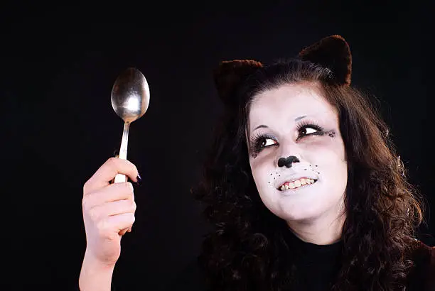 Portrait of cat-girl with spoon. Studio shot.