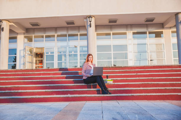 istock Young woman on university stairs lap top 1049335022