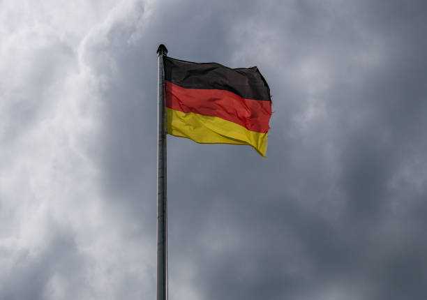 istock Flag of Germany against the cloudy sky 1049335716