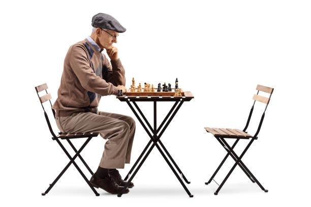 Elderly man planning his next move on a chessboard isolated on white background