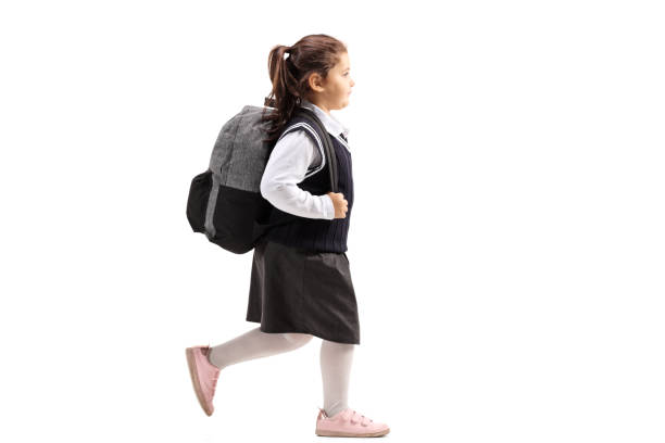 istock Schoolgirl with a backpack in a uniform walking 1049342504