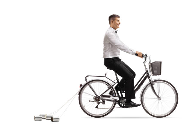 istock Groom riding a bicycle with wedding tin cans behind 1049343140