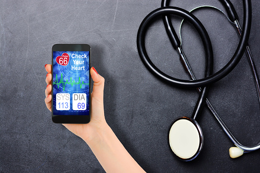 Blood pressure checking or tracking with smartphone and stethoscope on blackboard