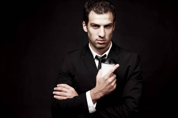 istock Brutal guy in a black suit with coffee. 1049346890