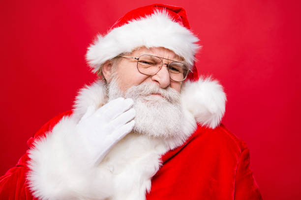 Aged mature stylish confused moody frustration grandfather Santa in costume glasses touch hand gloves to cheek make isolated on red background Aged mature stylish confused moody frustration grandfather Santa in costume glasses touch hand gloves to cheek make isolated on red background angry hairstylist stock pictures, royalty-free photos & images