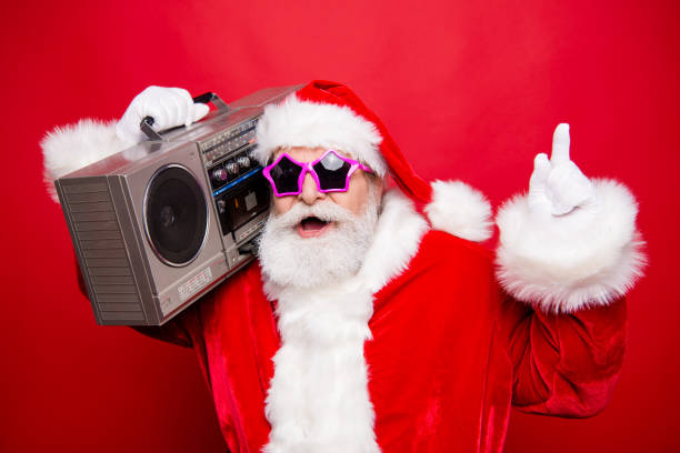 deseo de invierno diciembre noel eva elegir opción de navidad. barba blanca con estilo envejecido santa en espectáculos traje sombrero indicar punto de mostrar escuchar audio radio sonido aislado sobre fondo rojo - retro christmas audio fotografías e imágenes de stock