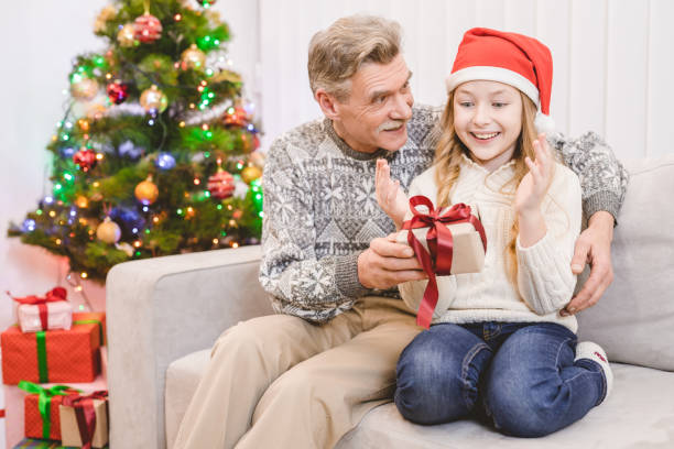 le vieil homme heureux, donnant une boîte-cadeau à un granddoughter - granddoughter photos et images de collection