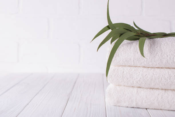 istock Spa composition on wooden table. Stack of three white fluffy bath towels with eucalyptus branch. Copy space 1049354646