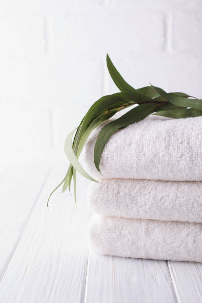 istock Spa composition on wooden table. Stack of three white fluffy bath towels with eucalyptus branch. Copy space 1049354648