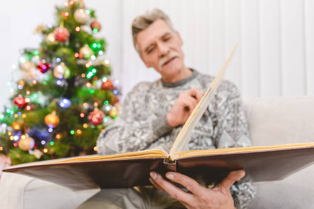 istock The old man hold a book near the christmas tree 1049355180