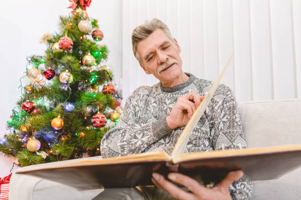 istock The old man hold a book near the christmas tree 1049355194