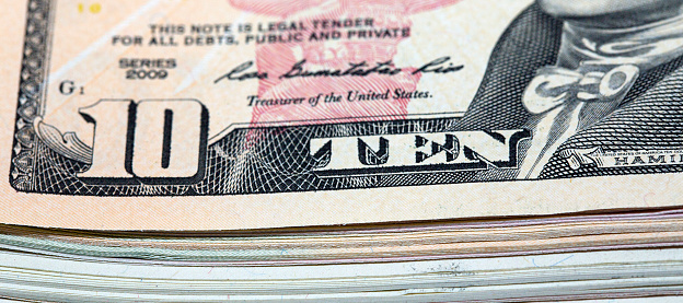 Close up of a stack of American ten dollar bills with selective focus in a panoramic format.