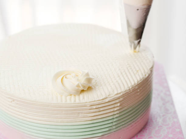 istock Confectioner topping cakes with cream using a pastry bag, 1049357840