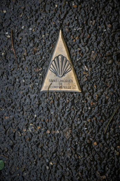 Camino de Santiago direction marker embedded in road near Saint-Jean-Pied-de-Port, France Camino de Santiago direction marker embedded in asphalt on road near Saint-Jean-Pied-de-Port, France. It point the direction to Santiago de Compostela (Saint-Jacques de Compostelle), 500 miles away. saint jean pied de port stock pictures, royalty-free photos & images