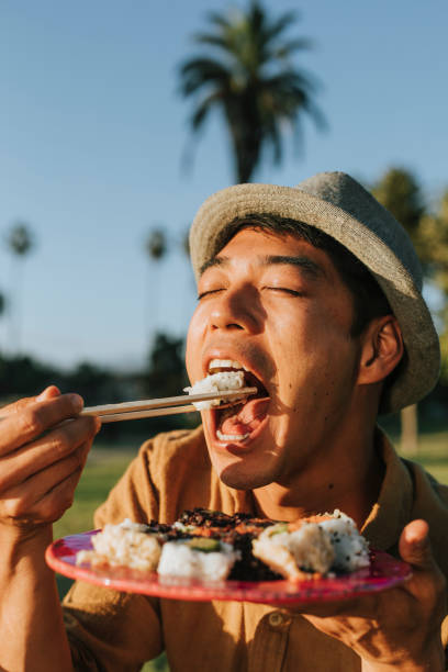 istock Man eating sushi in the park 1049369128