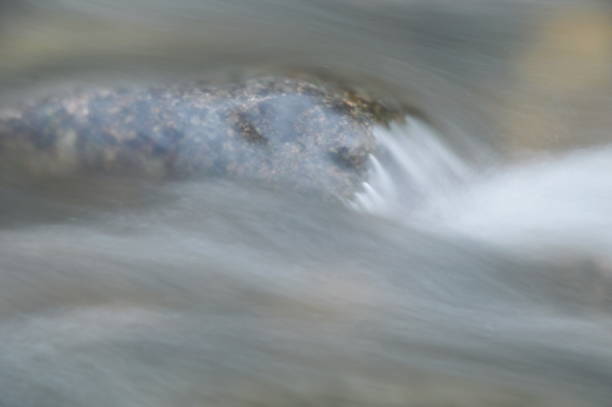acqua sfocata che scorre sulla roccia e spruzzi d'onda - indirection foto e immagini stock
