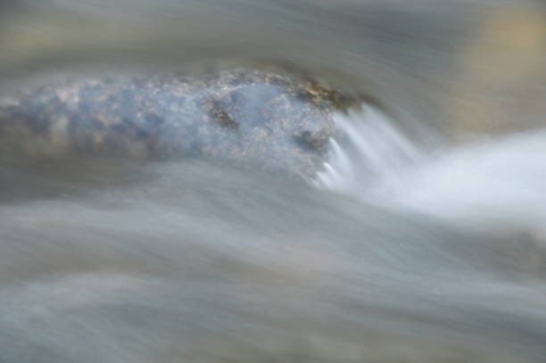 blurry water flowing on the rock and wave splashing - indirection imagens e fotografias de stock